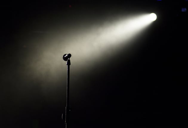 Photo of a microphone on an empty stage, under a spotlight