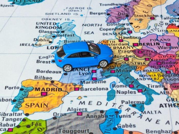 Small blue toy car over a map of Europe.