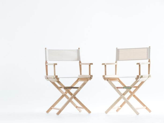 Two directors chairs next to each other on a white background.