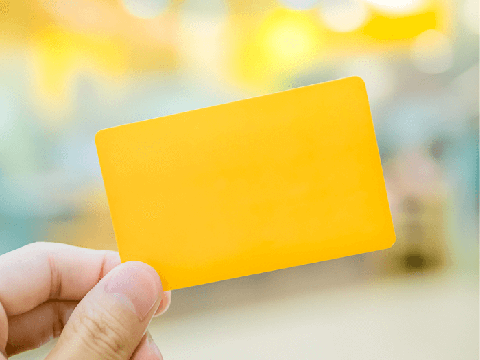A hand holding a yellow rectangle membership card.