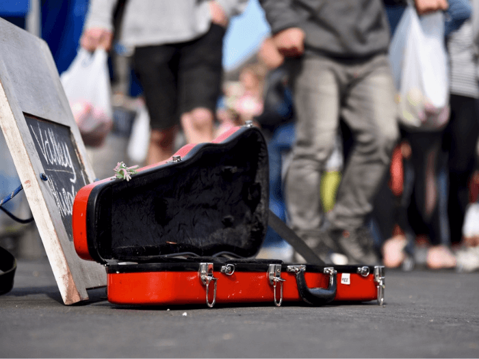 A violin case open on the street for donations from the public for a busking performance.