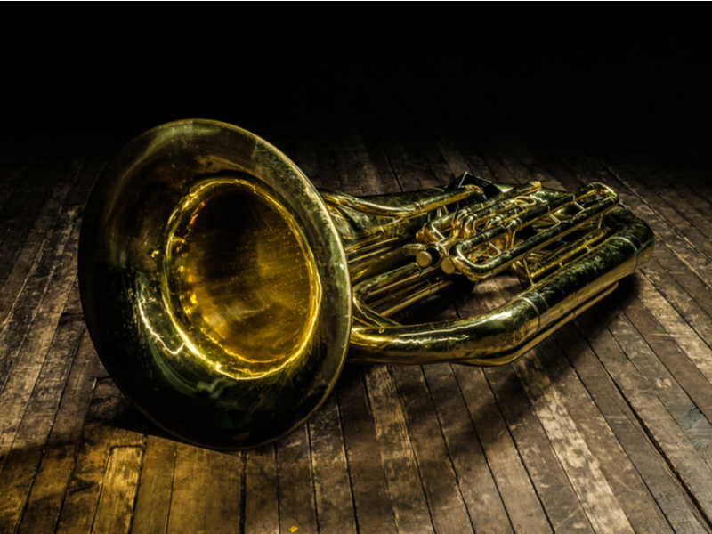 Golden euphonium lies on a brown wooden stage in the light of a spotlight