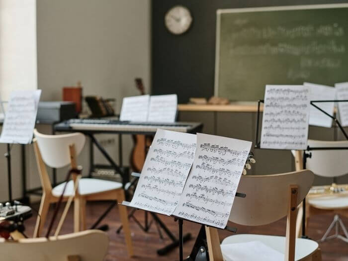 Sheet music on music stands in empty modern classroom.