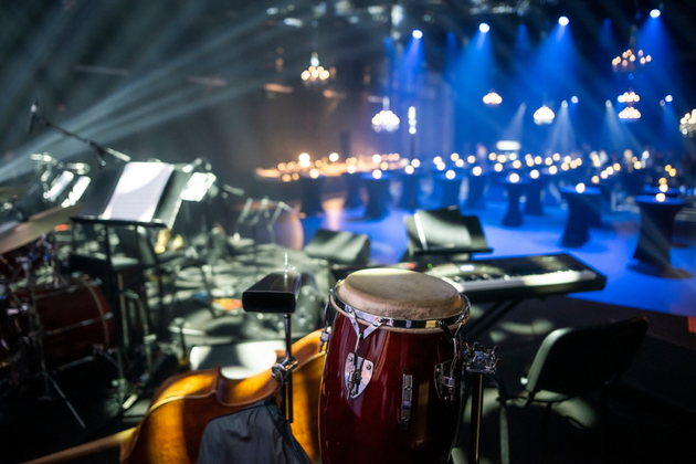 Photograph of what appears to be an empty theatre pit set up for musicians, with a drum, double bass and electronic keyboard set out.