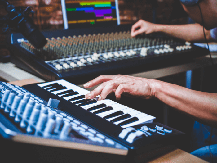 Musician playing midi keyboard synthesizer in a recording studio,