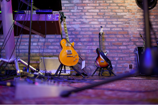 Photograph of a couple of guitars set back stage in an indoor venue