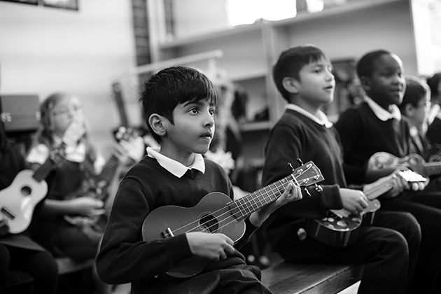 Primary aged children take part in a classroom ukulele lesson.