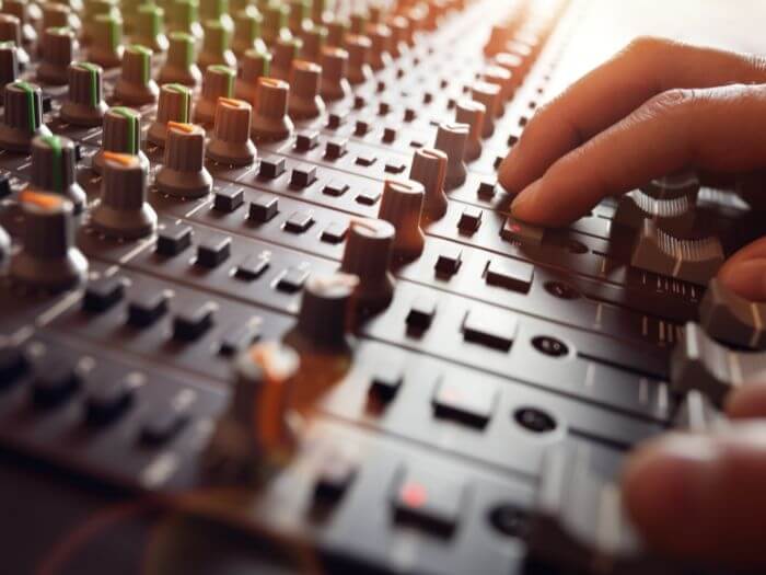 Close up of hands on a mixing desk.