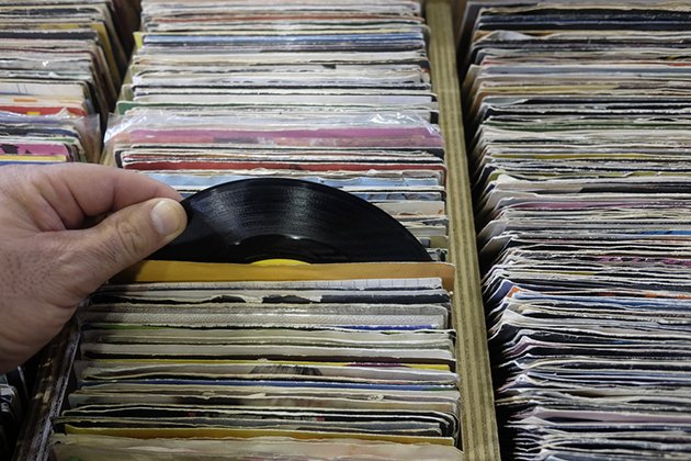 Person's hand shuffling through records at a vinyl sale