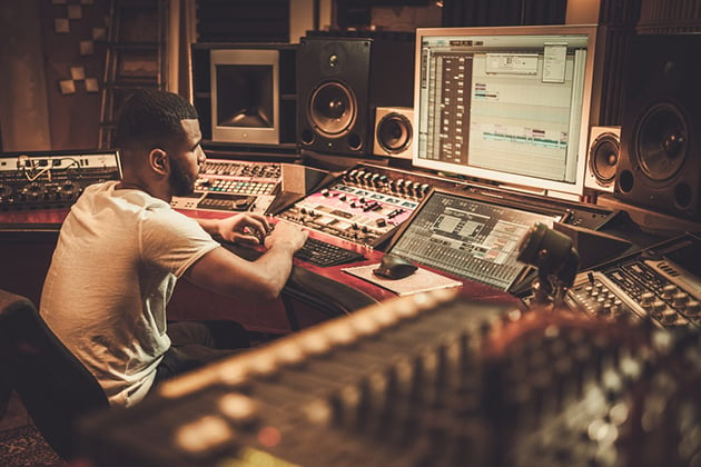 Photograph of a person working at a recording studio deck.