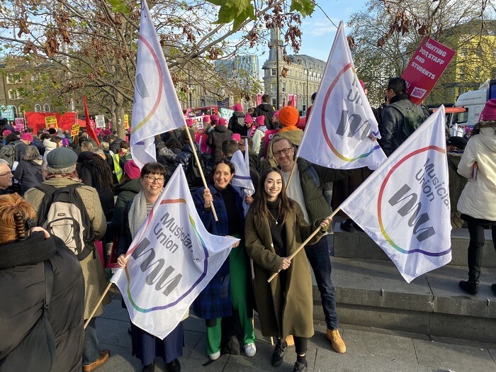 MU officers and organisers hold up MU flags at a busy UCU rally.