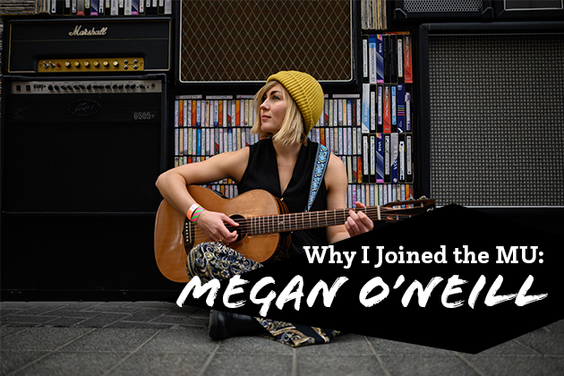 Photograph of Megan O'Neill sitting in front of an amplifier with a guitar