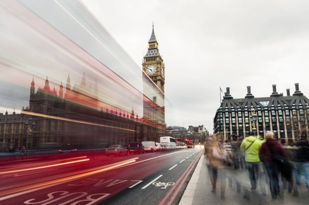 Stylized photograph of the Houses of Parliament from across Westminster Bridge, with traffic rushing by.