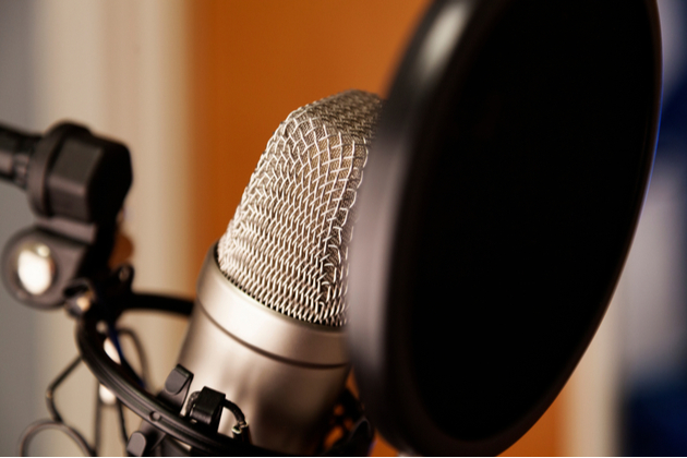 Photograph close up to a microphone set up in a recording studio.