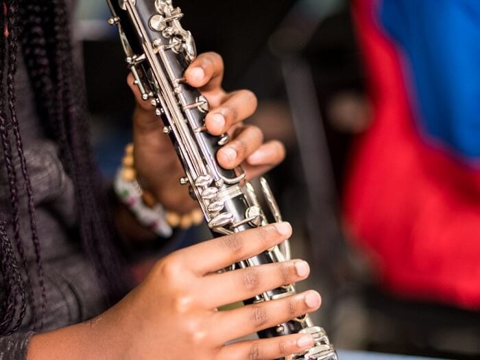 Hands on a clarinet in an informal setting, blurred background